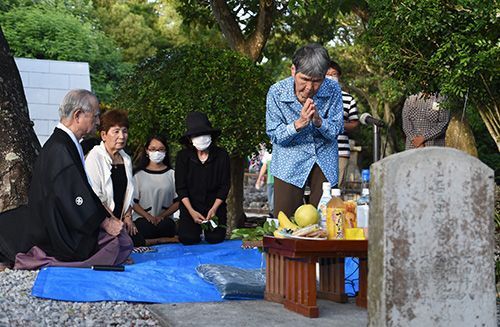 大田さん一家の冥福と恒久平和を祈る親族の山城千代さん（右）＝19日夕、糸満市伊原の「赤心之塔」